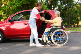 woman helping the elderly woman get into the car