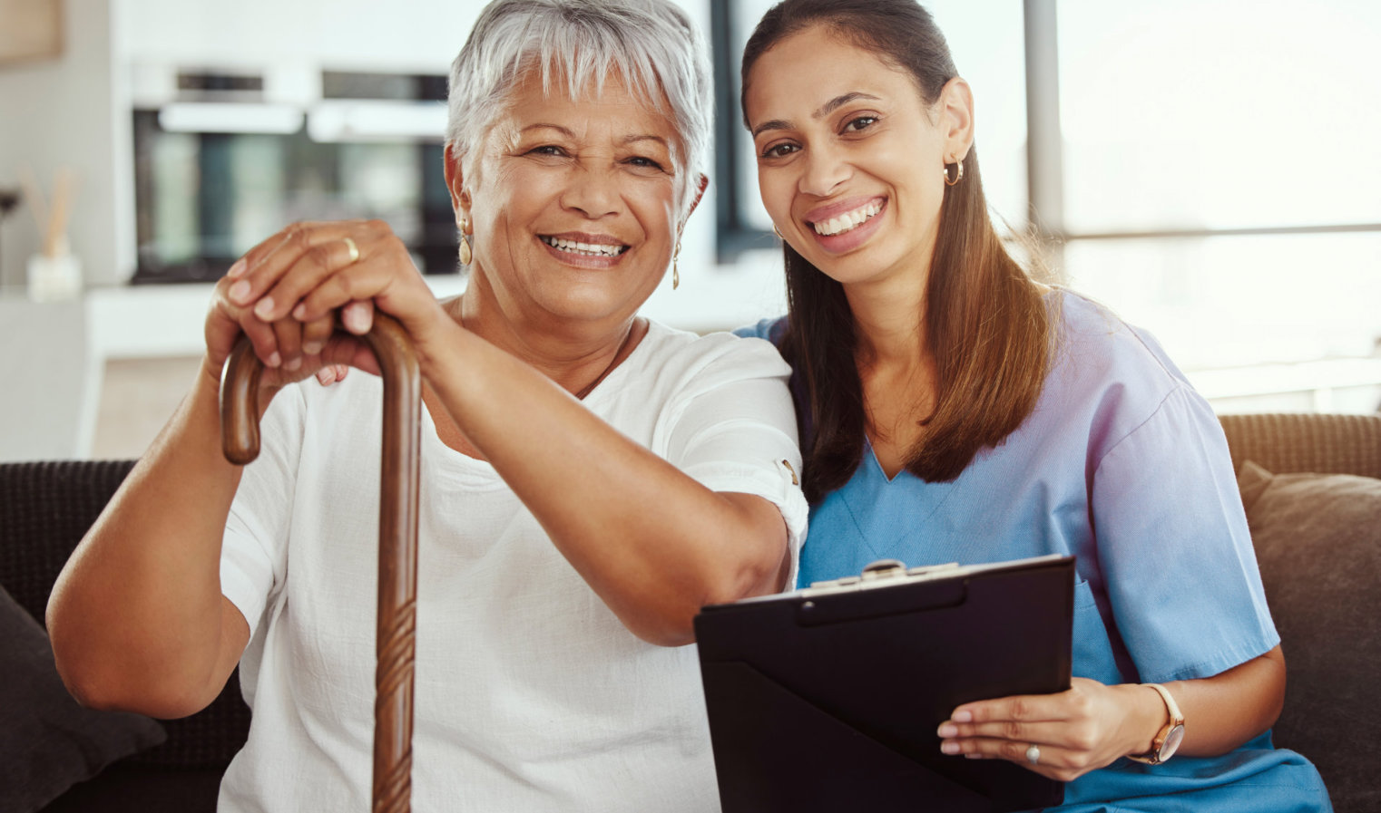 caregiver holding a clipboard and her senior woman patient